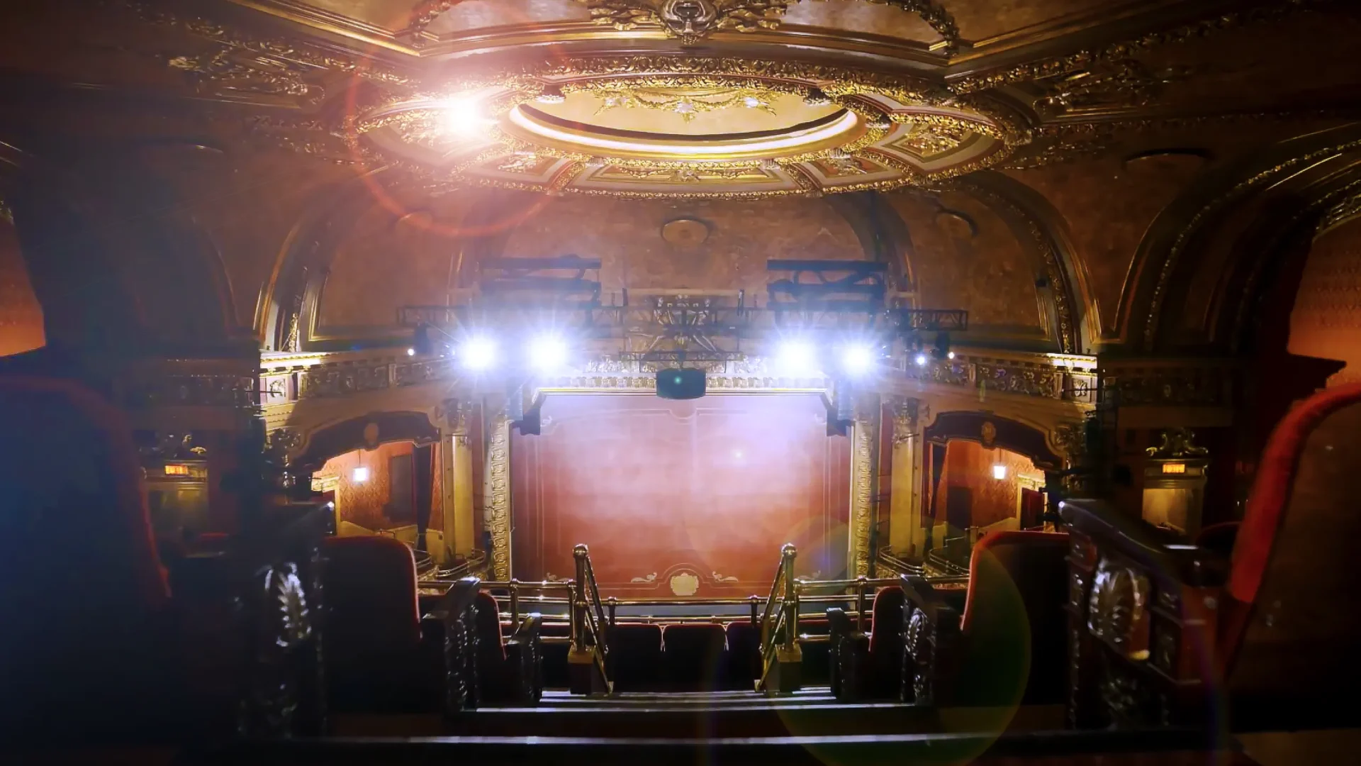 photo inside the Elgin theater, bright stage lights on, all the red velvet seats and gold ceiling details fully restored.